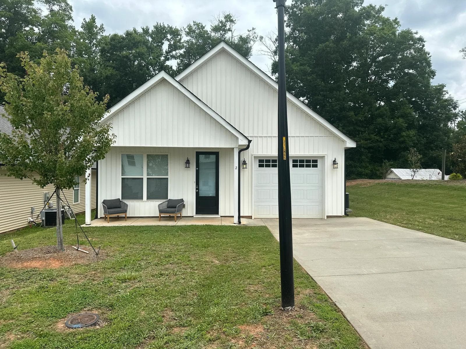 Exterior of 2 Solis Court — a white board-and-batten farmhouse with covered front porch and garage in Travelers Rest, SC